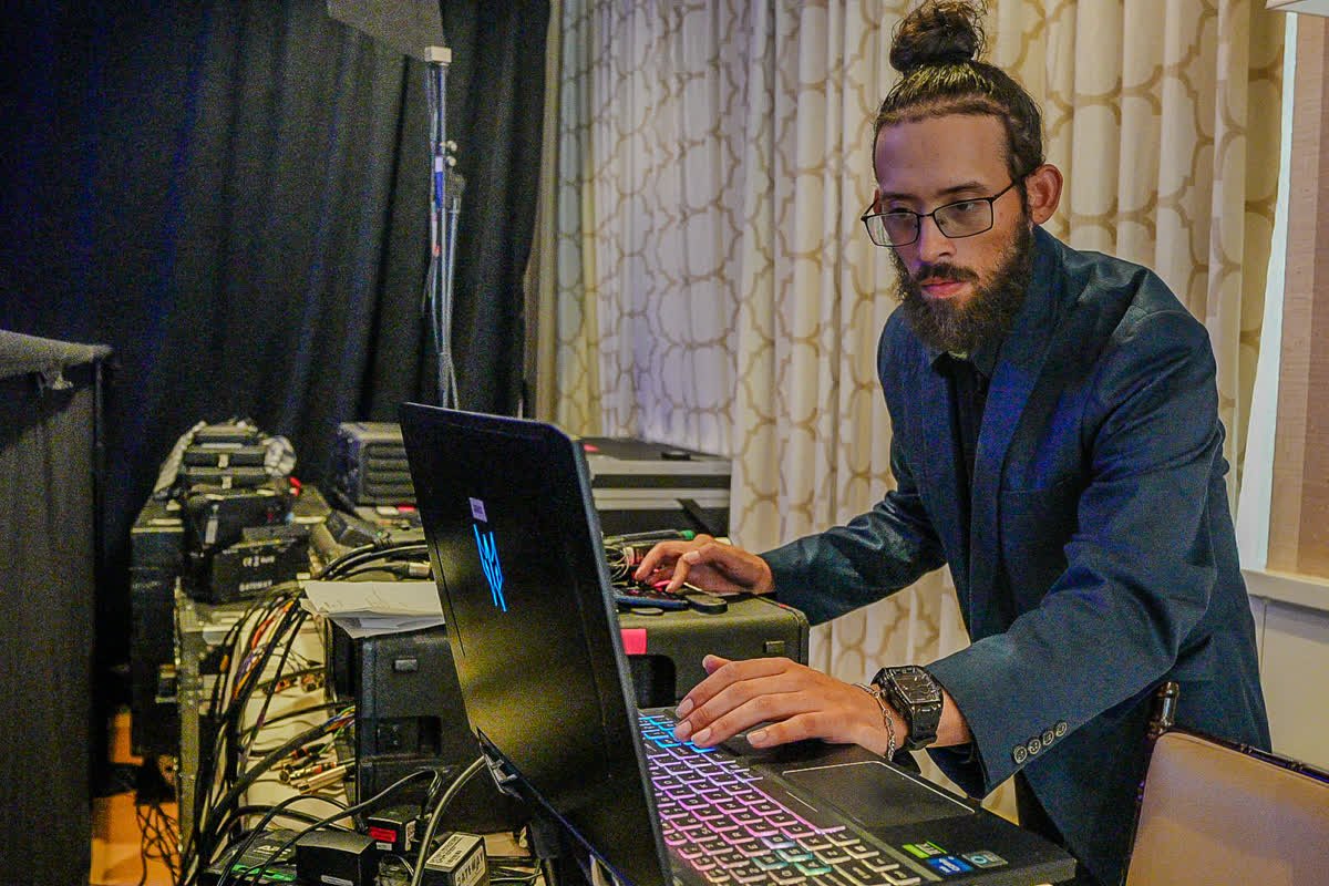 David Rodriguez mixing front of house at a corporate event, working from a laptop beside the rack