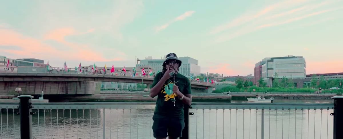 Tye Cooper holding a microphone by the water at sunset